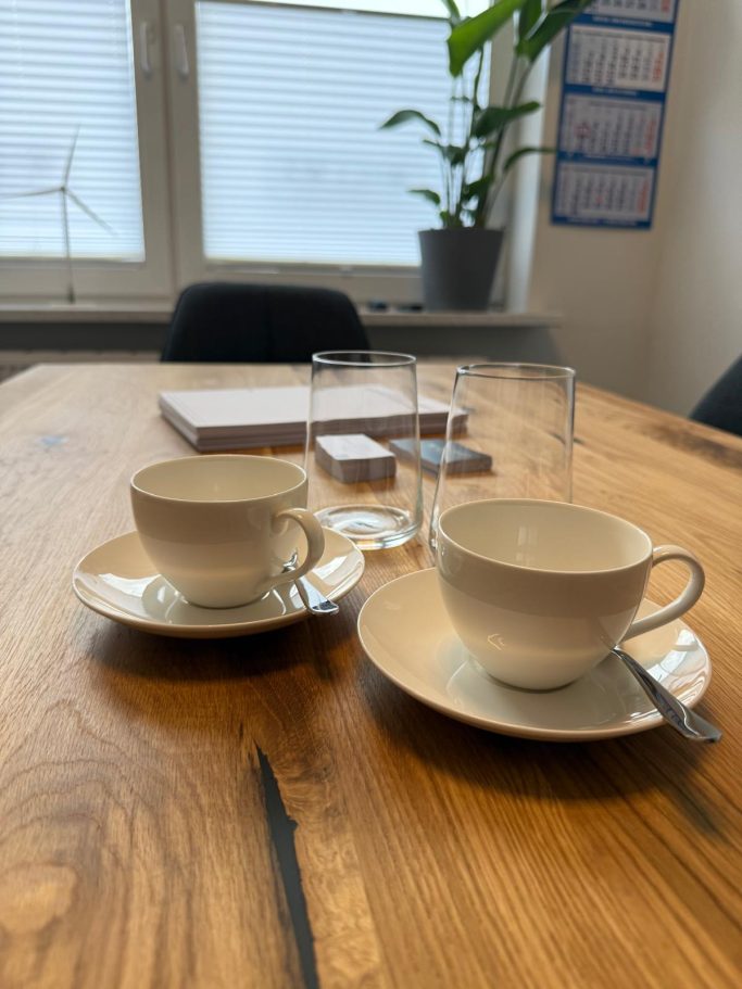 Kaffee und Gläser auf Besprechungstisch Zwei Tassen und zwei Gläser auf dem Besprechungstisch aus Holz.